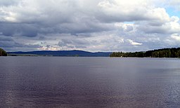 Utsikt från badplatsen i sjöns södra ände. Till höger Grills och i mitten Mårtens holme, och bakom den Kyrkviken och Fjällberget med vindkraftverk