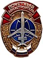 Нагрудный знак «Почётный авиастроитель Российской Федерации» (вариант 1990-х годов с красной лентой вверху, лентой цветов российского флага внизу, силуэтом самолёта Ил-62 и винтовой закруткой)