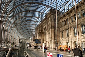 The forecourt of the Strasbourg train station lies behind and under a curved glass wall