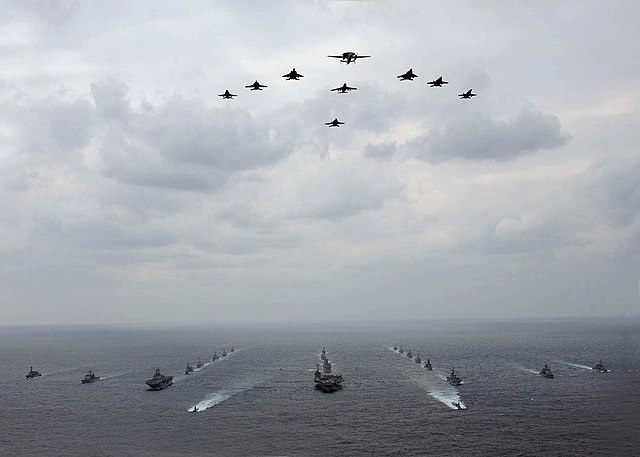 A mixed aircraft and ship formation of military vehicles during an exercise with USN and JASDF vehicles.