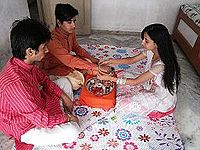 a sister with aarti plate tying rakhi