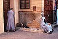 "A_scene_from_the_Moroccan_city_of_Marrakesh,_where_the_man_and_woman_appear_back_to_back,_as_if_they_are_fighting_each_other,_while_the_cat_between_them_is_trying_to_mend_the_broken_hearts.jpg" by User:Drugstore95