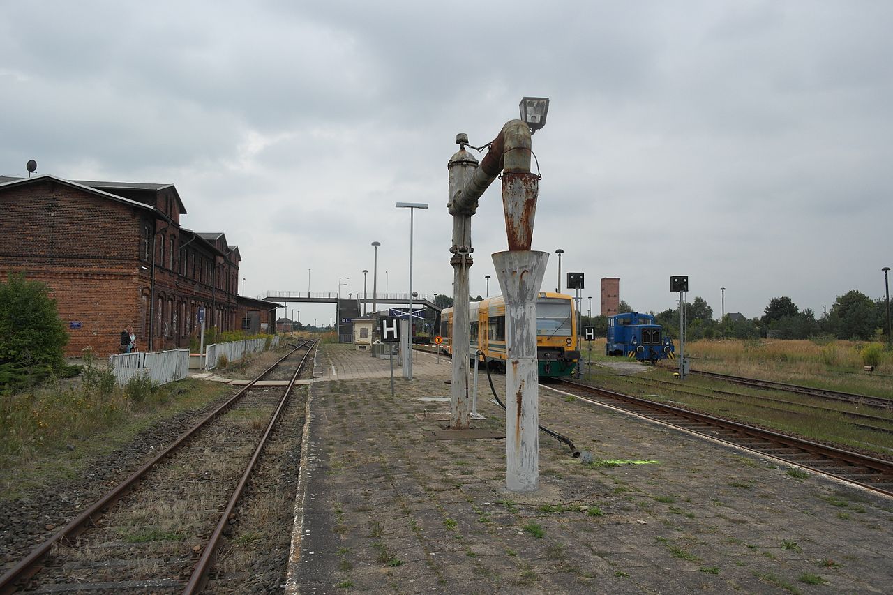 Bahnsteige mit denkmalgeschütztem Wasserkran, Empfangsgebäude und Nahverkehrszug im Jahr 2013