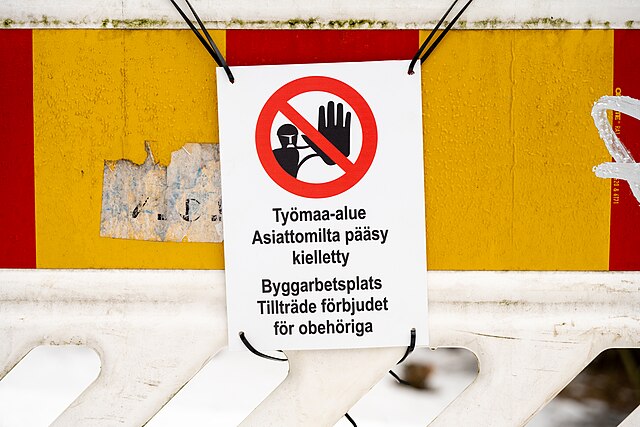 A bilingual "no trespassing" sign at a construction site in Helsinki, Finland (upper text in Finnish, lower text in Swedish)