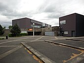 De ingang van de school, waarvan we twee moderne kubusvormige gebouwen kunnen zien.