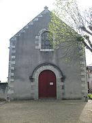 Photographie en couleurs de la façade d'un édifice religieux percée d'une porte surmontée d'une baie.