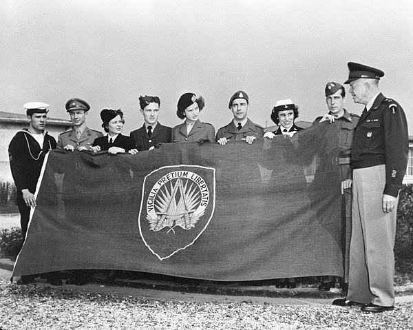 Gen. Eisenhower in front of the flag of SHAPE on 8 October 1951