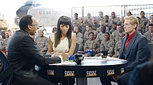 Champion between Stephen A. Smith (left), and Skip Bayless (right), filming First Take at Joint Base McGuire-Dix-Lakehurst in 2014 First Take Salute the Troops broadcast.jpg