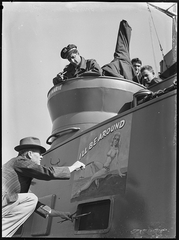 Harry Wann paints a "pin-up" girl on a PT boat, Australia, 1944