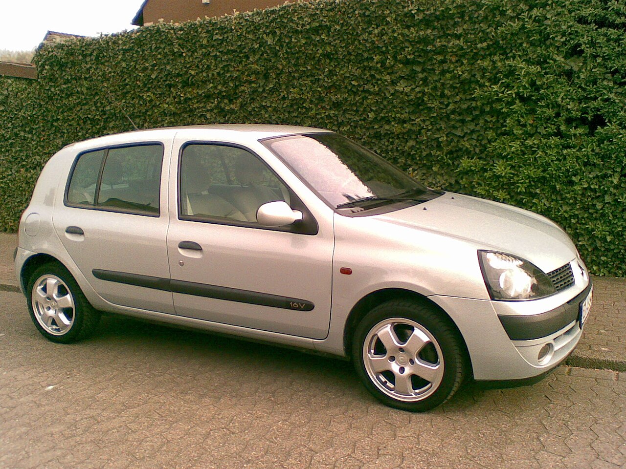 Tuned silver renault clio ii parked in front of a school on Craiyon