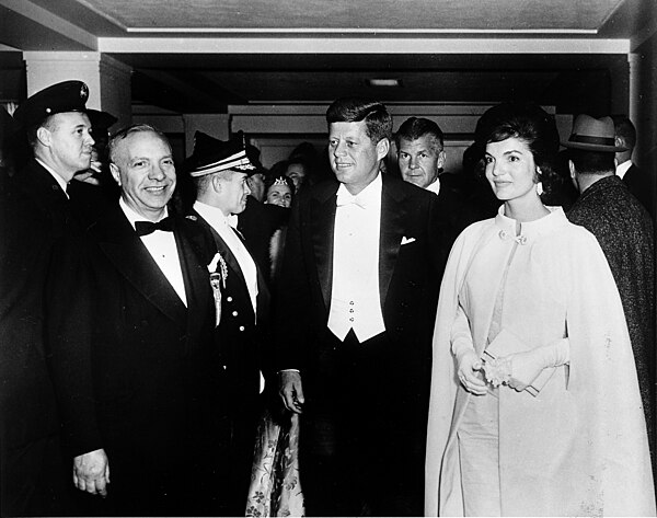 President John F. Kennedy, wearing white tie, and First Lady Jacqueline Kennedy, wearing a gown designed by Ethel Franken of Bergdorf Goodman, arrive 