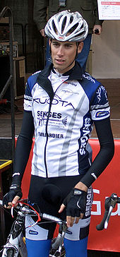 Фотография велосипедиста, стоящего и держащего велосипед рядом с собой