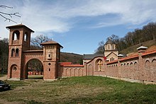 Bešenovo Monastery a red brick building with an arched entry and a tower