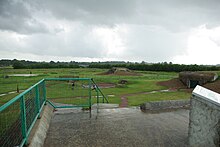 Vue du site de la batterie de Merville prise depuis le toit de la casemate no 2. On peut voir de droite à gauche : les casemates no 3 et no 4, les emplacements extérieurs du canon no 3 et derrière du canon no 4, et le toit de la soute à munition.