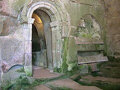 Parte da fachada da antiga igrexa rupestre co arco románico de entrada á capela da Epístola, e o nicho cos sepulcros de dous cabaleiros xacentes.