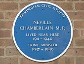 Round blue plaque on a brick wall. It says "BIRMINGHAM CIVIC SOCIETY", "NEVILLE CHAMBERLAIN M.P.", "LIVED NEAR HERE 1911–1940", "PRIME MINISTER 1937–1940".