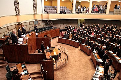 Eduskunnassa kansanedustajat keskustelevat ja äänestävät yhteisistä asioista täysistuntosalissa. Puhetta korokkeella johtaa puhemies.