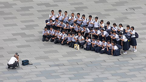 Photographer taking a group photograph of smiling students in front of the Tokyo station, Marunouchi, Japan