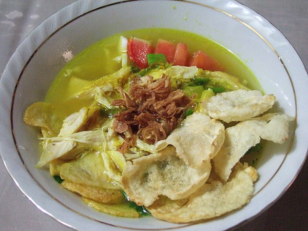 Soto ayam with clear yellow broth, garnished with emping crackers and fried shallot