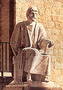 Statue en pierre claire représentant un homme assis.