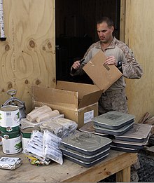 A U.S. Marine food service specialist with several Unitized Group Rations U.S. Marine Corps Cpl. Daniel Russo, a food service specialist with Security Force Advisory and Assistance Team 2-215, prepares meals at Forward Operating Base Nolay, Afghanistan, Nov. 21, 2013 131121-M-WC184-394.jpg