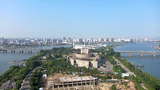 Yanggak Island in August 2012; from front to rear: new health complex's construction site, International Cinema Hall, Yanggak Bridge and Yanggakdo Stadium