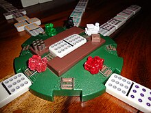 Commercially-produced station hub (pat. Fundex, 2006) with notches for eight spokes (five in use) and train-shaped player markers; the game in progress is using the double-twelve domino as the engine Zanita's Train Dominos.jpg