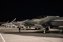 Multiple fighter jets bearing the Israeli insigna, parked in an air base at night