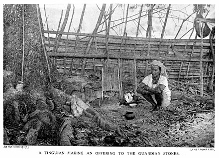 1922年、フィリピンのイトネグ族の女性シャーマンが、ピナリングと呼ばれる水に溶けた石に宿る村の守護アニト、アプデルに供え物をしている写真。[29]
