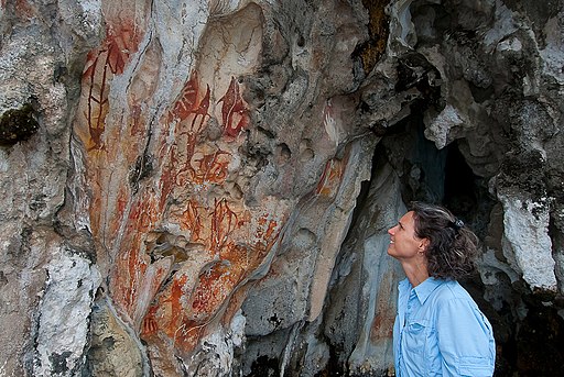 A tourist looks are rock art in West Papua, Bird's Head Seascape