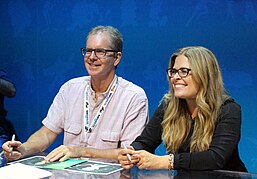 A gray-haired, bespectacled Chris Buck and a blonde-haired Jennifer Lee, signing lithographs at D23 Expo