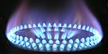 Close-up image of a natural gas burner on a stove showing the characteristic blue hue of a natural gas flame.