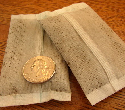 A pair of air-activated disposable hand warmers, US quarter for scale.
