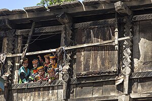 Kalash girls looking from the window of traditional wood home with beautiful carvings.jpg