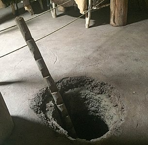 Hullet ned til en dyb grube i en rekonstrueret mandan-hytte med en stige (North Dakota)