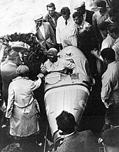 Foto de alto ângulo de um grupo de pessoas ao redor de um carro de corrida.
