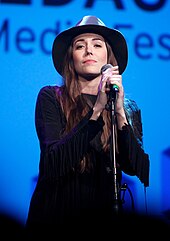 Foto einer Frau, die mit einem Mikrofon auf einer Bühne steht