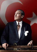 Mustafa Kemal Ataturk looking through a train window over Turkish flag.jpg