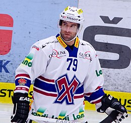 Fargebilde av en hockeyspiller 3/4 rygg og lener seg fremover