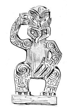 Carved human figure in traditional Māori style facing forward with tongue protruding, touching head with right hand.