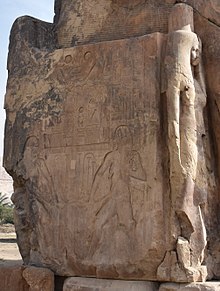 Side panel detail showing two flanked relief images of the deity Hapi and, to the right, a sculpture of the royal wife Tiye Side panel of Colossi of Memnon 2015 2.JPG