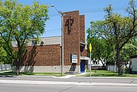 Une église en briques brunes à deux étages avec un clocher moderne.