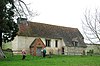 Eine kleine, schlichte Kirche, weitgehend mit Ziegeldach, einem Backsteinportal und einem Glockenstuhl am westlichen Ende