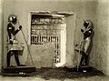 Ka-veistokset esikammiossa hautakammion oven molemmin puolen. Takana näkyvät hautakammion täyttäneet hautakaapit, joita oli useampi sargofagin ympärillä.