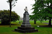 Carved bust of a man on a plinth in a lawn