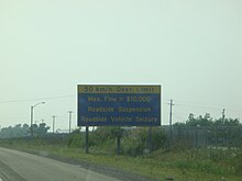 A sign on the Queen Elizabeth Way in Ontario, Canada, warning of a $10,000 fine, a roadside licence suspension, and a roadside vehicle seizure if motorists exceed the speed limit by 50 km/h or more. $10000 fine.jpg