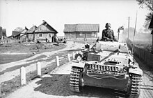 A Panzer II during Operation Barbarossa in 1941 moves along a road outside a village. Bundesarchiv Bild 101I-265-0003-18A, Russland, Panzer II.jpg