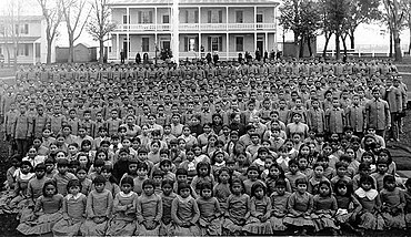 Native youth in front of Carlisle Indian Industrial School in Pennsylvania c. 1900 Carlisle pupils.jpg