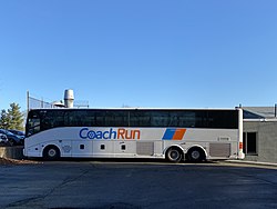 a white bus stopping at the bus stop