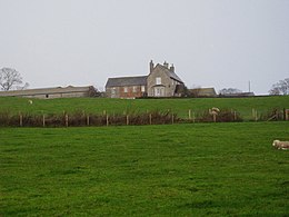 View across garden to fields. Small redbrick cottage to left.